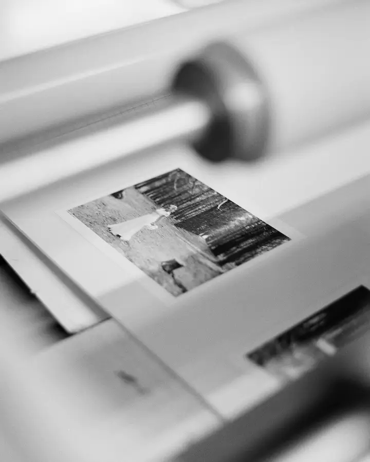 A fine art print passing through an archival mounting machine