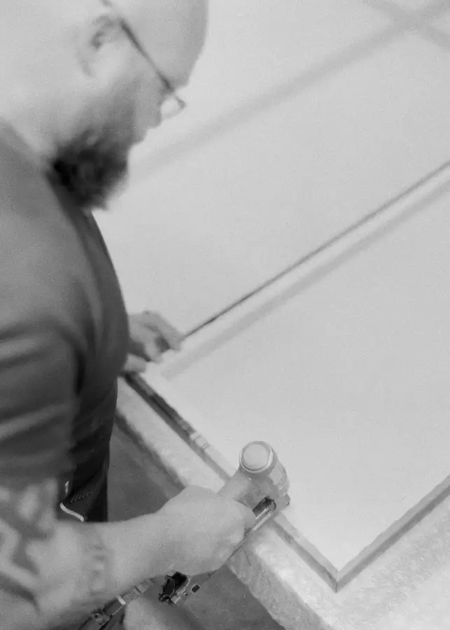 Craftsman using a nail gun to secure a timber frame