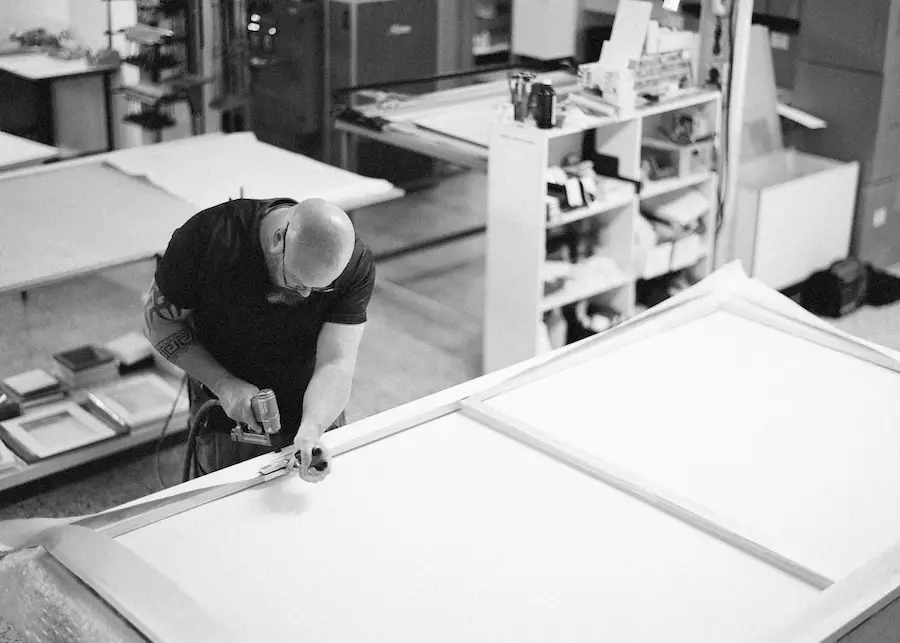Craftsman stapling a large canvas in the workshop