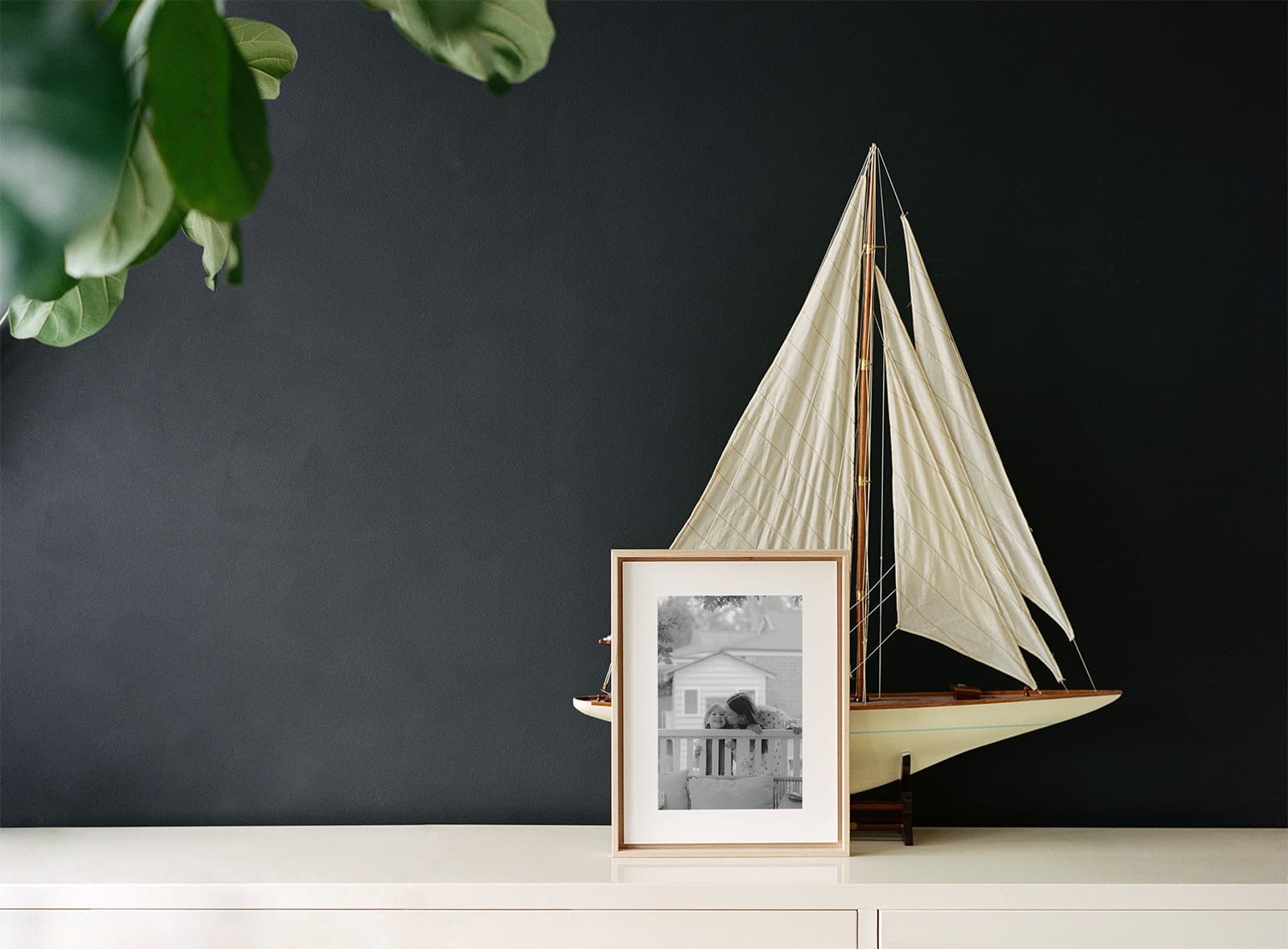 Framed black and white photograph displayed on a sideboard beside a model sailboat